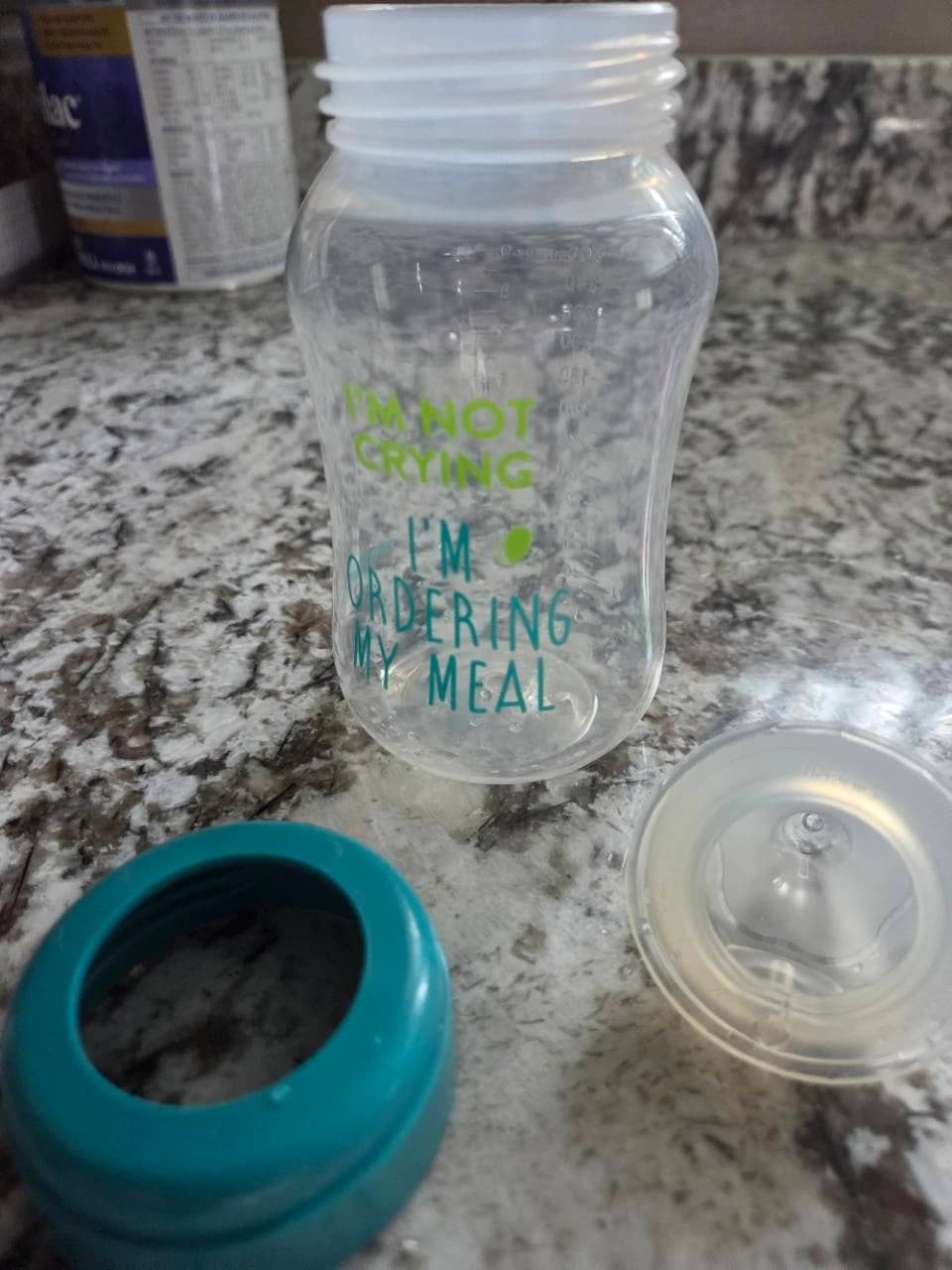 Our open baby bottle with a teal collar and translucent nipple laid separately on the kitchen counter
