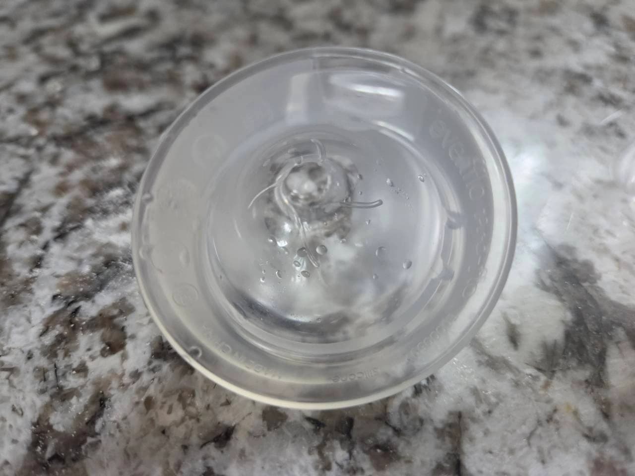 Underside of our translucent bottle nipple showing faint molded lettering around the broad outer rim