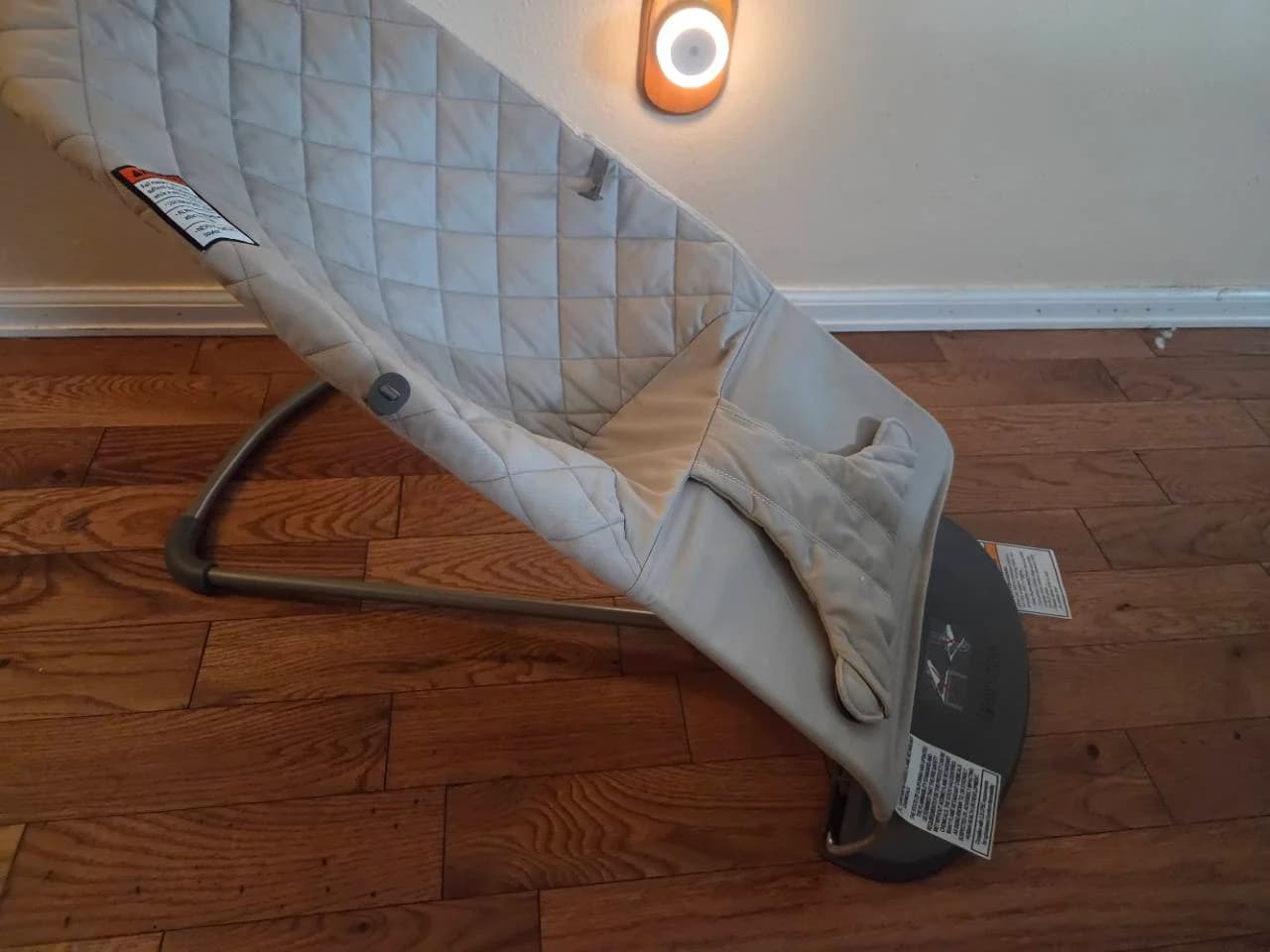 Our empty BabyBjörn bouncer with light quilted fabric, a gray metal frame and black base at home