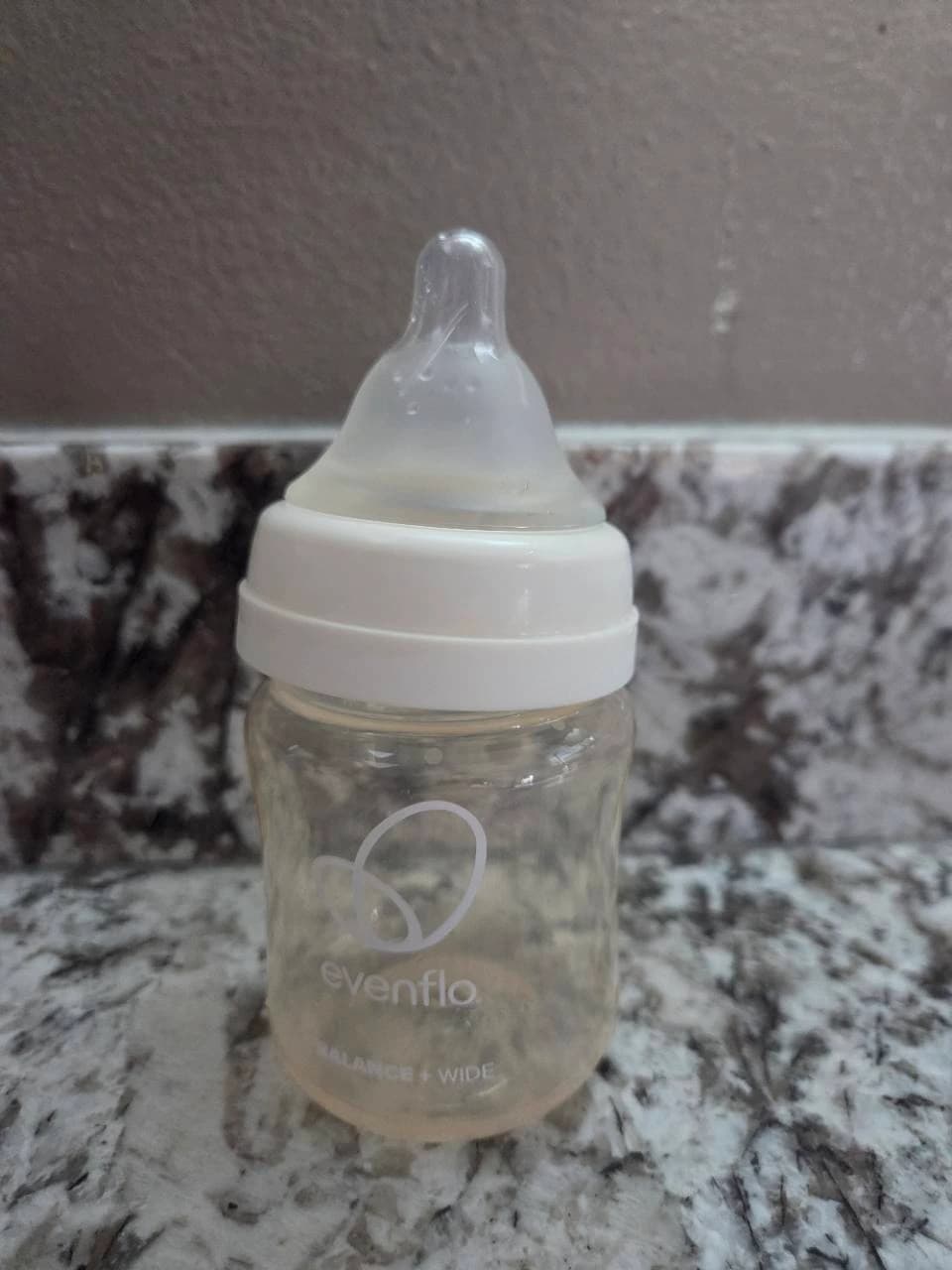 Our Evenflo Balance+ Wide bottle with a white collar and translucent nipple attached, photographed on the kitchen counter
