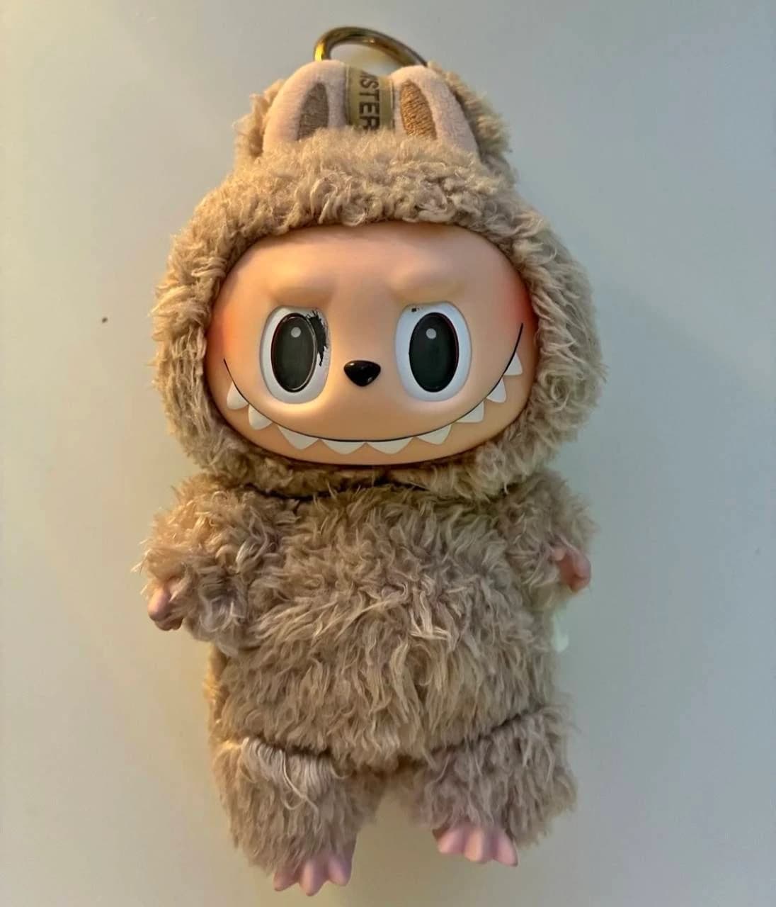 Brown furry Labubu keychain with a gold ring above its ears