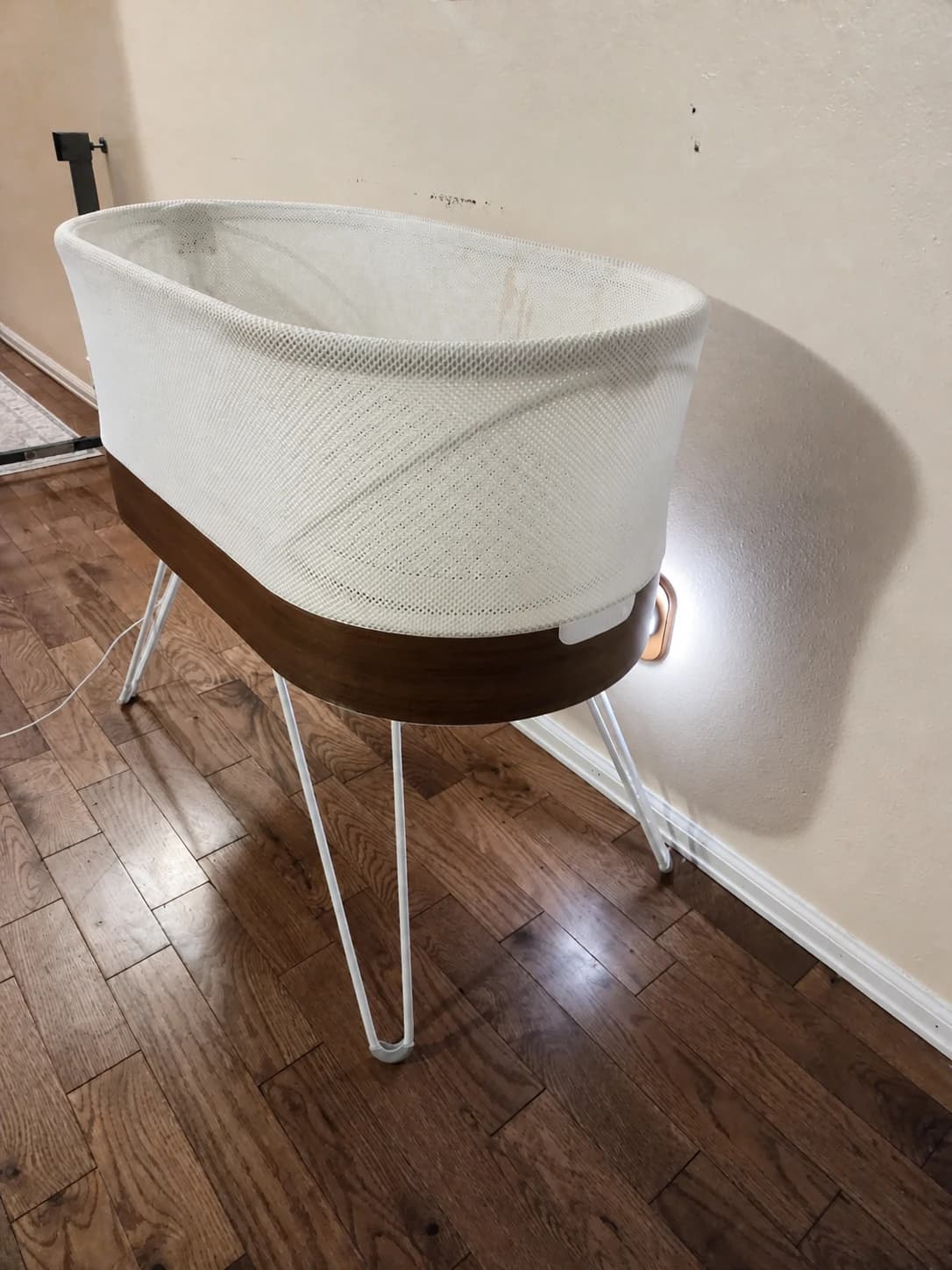 Our empty SNOO with white mesh sides, a wood-tone base and metal legs at home